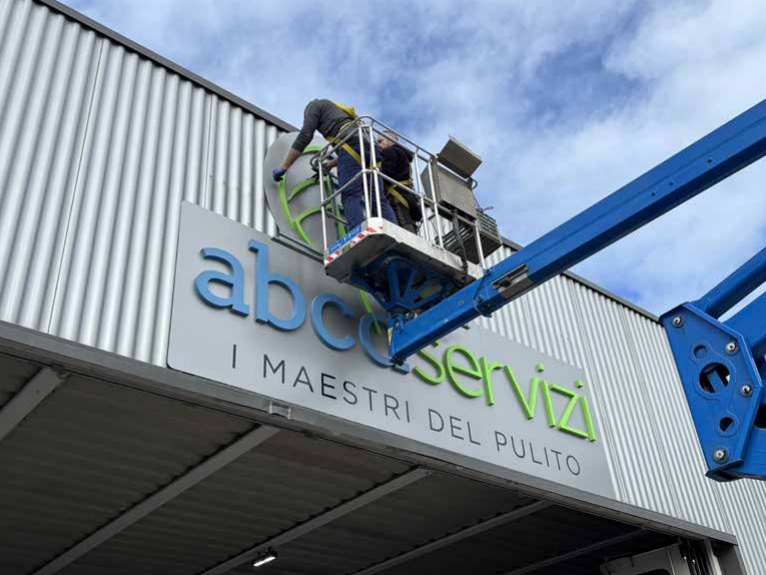 Tecnici FORME installano un'insegna su piattaforma aerea